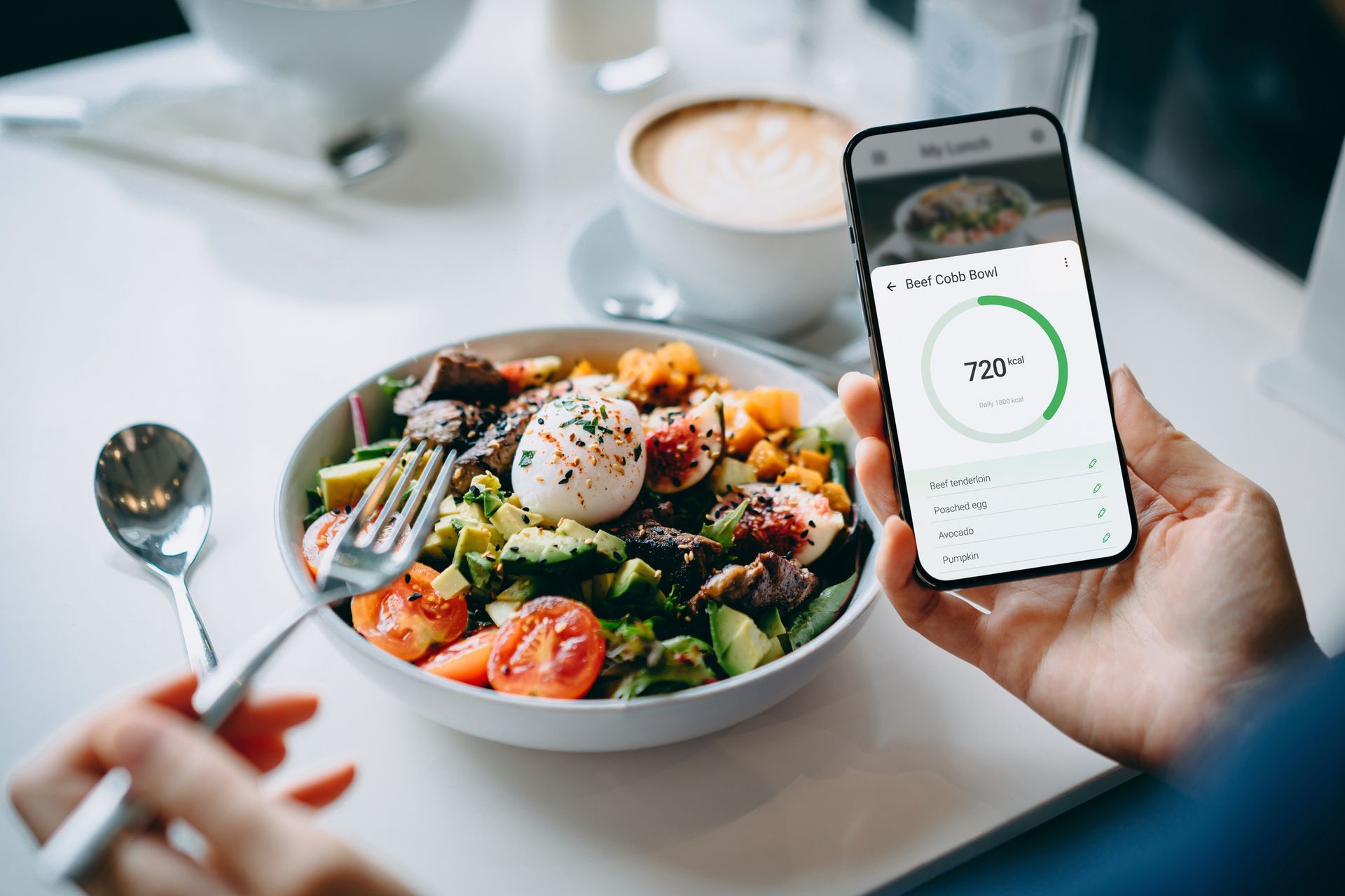 Meal tracking on a smartphone beside a plate of food